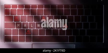 Banner top view of laptop keyboard with "malware" message on buttons and red light. Security alert data protection business technology. Stock Photo