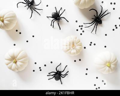 White Halloween background with white pumpkins, black spiders and black glitter on a white background. Halloween layout . Flat lay, top view Stock Photo
