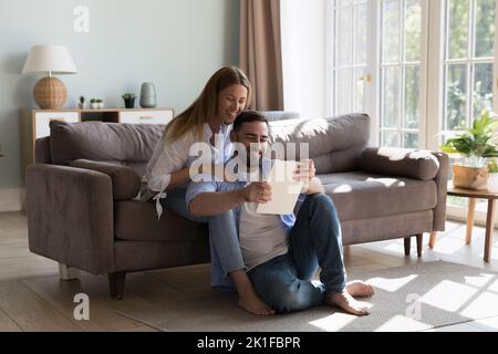 Happy millennial attractive couple of homeowners using tablet Stock Photo