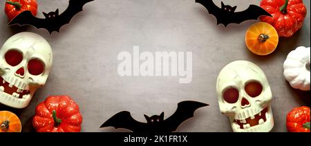 Holidays, decoration and party concept -scull, black bats and pumpkins halloween over gray background. Stock Photo