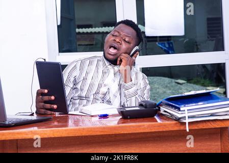 young serious businessman wearing a headset and having a video call on digital tablet in the office. Stock Photo