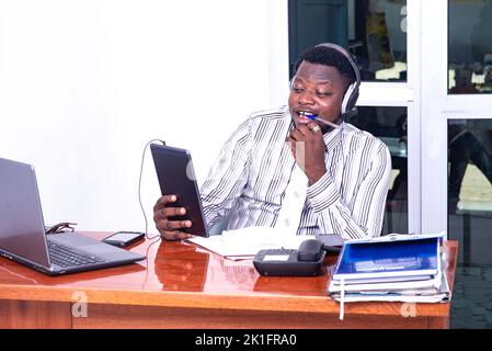young businessman wearing headset and having video call on digital tablet in office. Stock Photo
