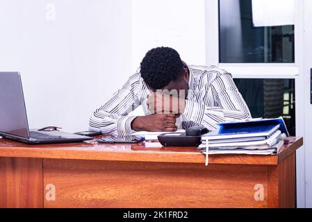 young frustrated businessman having problems sitting at the desk, leaning his head down and feeling loser. Stock Photo