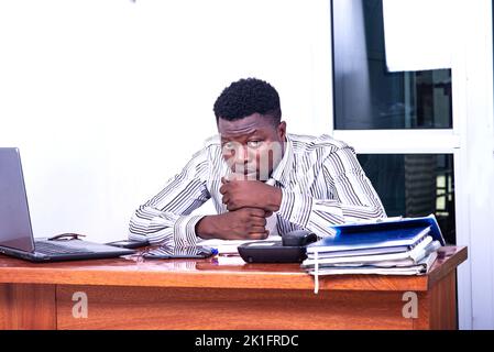 discouraged young businessman sitting at the desk having problems. Stock Photo