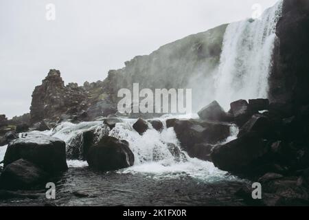 The waterfall of Oxararfoss in Thingvellir National Park, Iceland flowing from the river Öxará into the pool filled with rocks. Cold dark water and gr Stock Photo