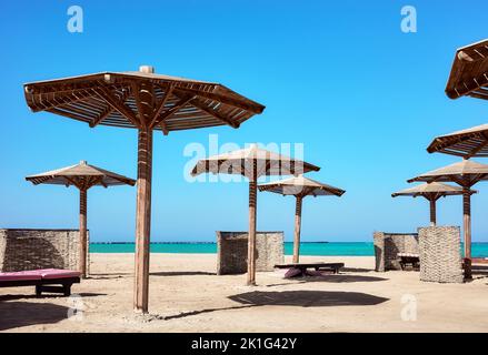 Wooden sun umbrellas, sunbed and windscreens on beach, Marsa Alam, Egypt. Stock Photo