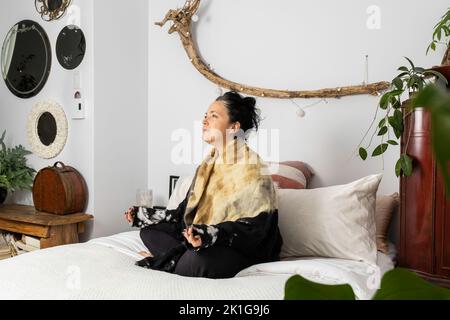 Middled-aged woman meditating sitting on her bed lost in her thoughts. High quality photo Stock Photo