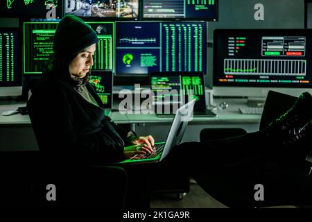 Professional female hacker typing virus code on laptop for cyber attack Stock Photo