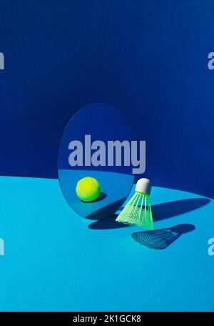 Badminton shuttlecock or birdie reflecting in mirror as tennis ball on blue background. Stock Photo