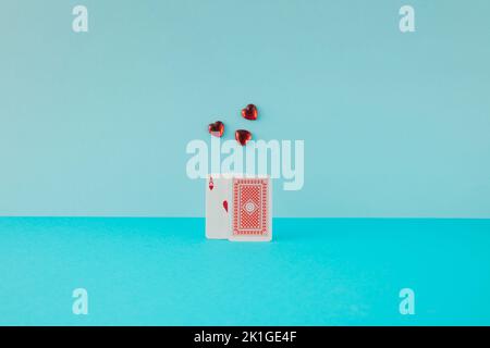 Two playing cards with ace of hearts and glass red hearts on blue background. Minimal concept. Stock Photo