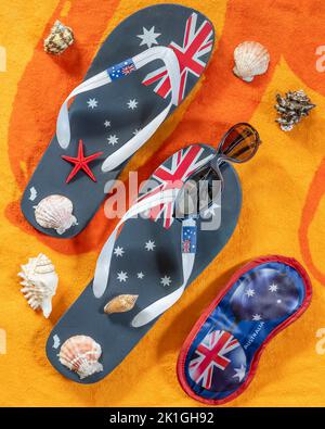 Eye mask and flip flops with Australian flag, shells and sunglasses on orange and yellow background Stock Photo