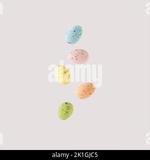 Styrofoam eggs of various colours falling through the air against white background. Stock Photo
