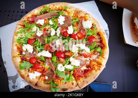 Traditional and authentic Italian pizza baked in wood fired oven. On table with ingredients. Stock Photo