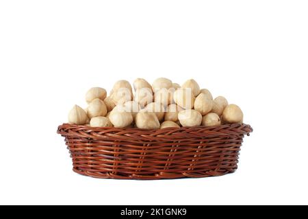 Tasty peeled and roasted organic raw hazelnuts in small brown wicker basket isolated on white background with selective focus. Stock Photo