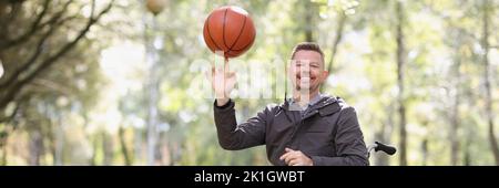 Smiling man in wheelchair holding basketball closeup Stock Photo