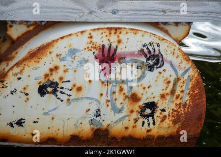 Abstract painted hand prints on old rusting oil drum. Stock Photo