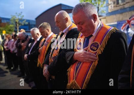 Brethren from the West Belfast Orange Hall on the Shankill Road in Belfast, bow their heads observe the national minute's silence in memory of Queen Elizabeth II. The country is observing one-minute silence to remember the Queen, with people invited to mark the occasion privately at home, on their doorstep or street, or at community events and vigils. Picture date: Sunday September 18, 2022. Stock Photo