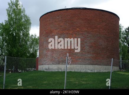 cylindrical brick building behind a mesh metal fence, deadpan photography Stock Photo