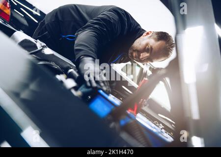 Car mechanic or car wash worker will clean the car engine with a cloth. Stock Photo