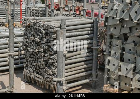 Stacked construction struts on construction site.Palette with gray metal scaffolding props. Skyscraper construction site Stock Photo