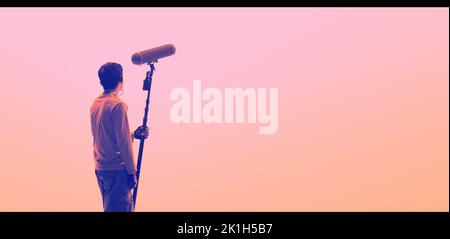 Boom Microphone for sound recording in film industry. Sound boom operator recording sound by microphone fisher for movie set in studio. Boom mic holds Stock Photo