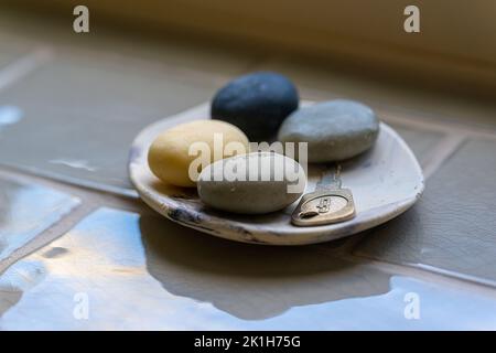 A small decorative dish containing a variety of small soaps on a tiled windowsill.UK Stock Photo