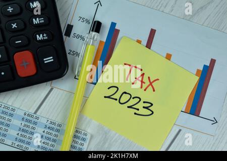 Concept of Tax 2023 write on sticky notes isolated on Wooden Table. Stock Photo