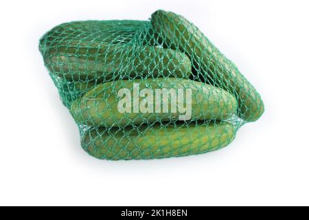 A pile / heap of green cucumbers in the green plastic net mesh / bag. Isolated on the White background. Space for text. Copy space. Close-up. Top view Stock Photo