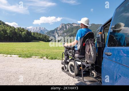 Man with disability a frequent traveller, getting off a van using the wheelchair lift after arriving in a mountain rest area Stock Photo