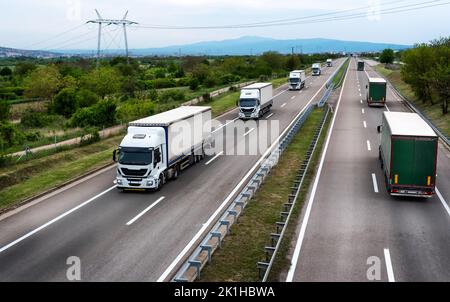White trucks on highway - heavy truck traffic on the highway in the evening Stock Photo