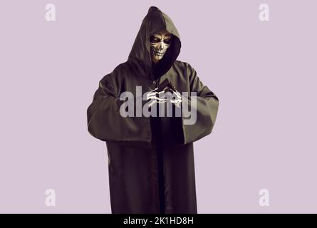 Man in scary Halloween costume of Mr Death standing isolated on light purple background Stock Photo
