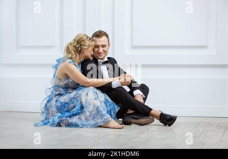 Young couple in luxury fashionable clothes sitting on floor and hugging Stock Photo