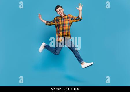 Full length portrait of carefree energetic man jumping enjoy free time isolated on blue color background Stock Photo