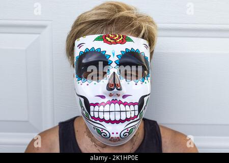 portrait of an elderly lady with a catrina mask celebrating Halloween and All Souls' Day, on a white background. Celebration, costume, party and mask Stock Photo