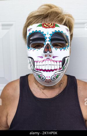 portrait of an elderly lady with a catrina mask celebrating Halloween and All Souls' Day, on a white background. Celebration, costume, party and mask Stock Photo