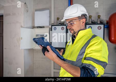 Electrical technician looking focused while working in a switchboard with fuses. Stock Photo
