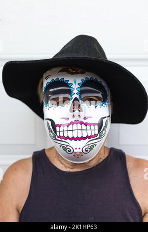 Portrait of an elderly lady with a catrina mask and hat, celebrating Halloween and All Souls' Day, on a white background. Celebration, costume, party Stock Photo