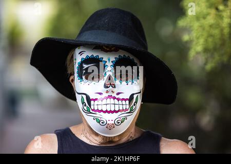 Portrait of an elderly lady with a catrina mask and hat, celebrating Halloween and All Souls' Day, on the street. Celebration, costume, party and mask Stock Photo