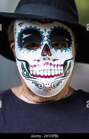 Portrait of an elderly lady with a catrina mask and hat, celebrating Halloween and All Souls' Day, on the street. Celebration, costume, party and mask Stock Photo
