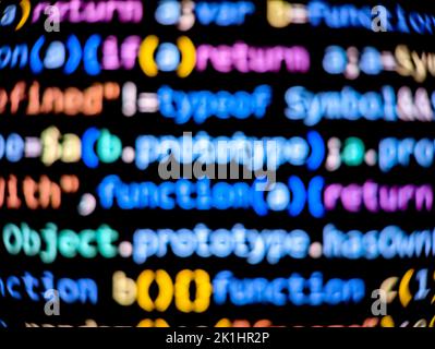 Blurred computer code on a digital screen with colorful characters displayed in dark mode on a black background Stock Photo