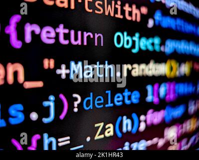 Pixelated view of computer code displayed on a laptop screen with bright colorful characters on a dark background Stock Photo