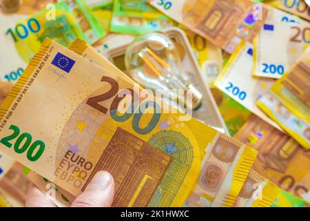 Electricity cost .Electric light bulb in hand on euro bills background. Rising electricity prices.Paying electricity bills. Payment for utility Stock Photo