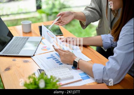 cropped shot, Two professional Asian financial analysts or accountant analyzing and reviewing a financial report together. Stock Photo