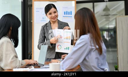 A professional businesswoman or female manager presents her financial analysis report in front of her team during the meeting. Stock Photo
