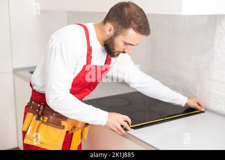 craftsman installs hob in kitchen. Household Appliance Installation Services Concept Stock Photo