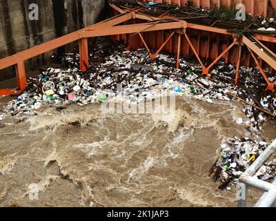 Aerial view of turbid brown forest water released by concrete dam drainage channels as water overflows in the rainy season with dry twigs and plastic Stock Photo