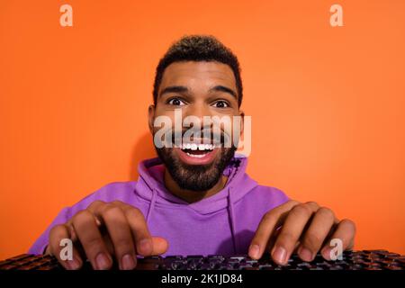 Photo of excited positive person hands typing keyboard toothy smile isolated on orange color background Stock Photo