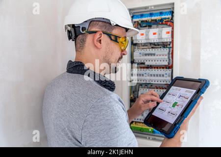 Electrical technician looking focused while working in a switchboard with fuses. Stock Photo