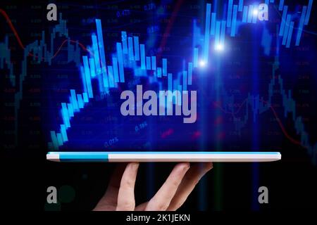 Stock market chart on blue background emerge from a tablet that a man holds Stock Photo
