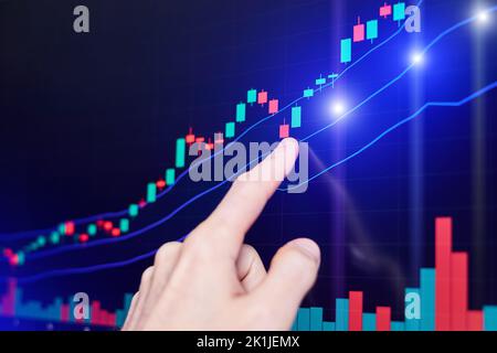 The trader points his finger at the Rising stock chart on the monitor Stock Photo